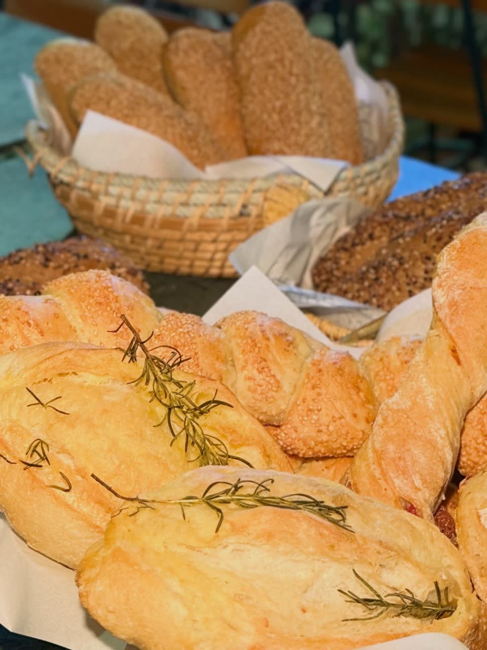 Cestas com pães de gergilim e pães rústicos de alecrim polvilhados de farinha